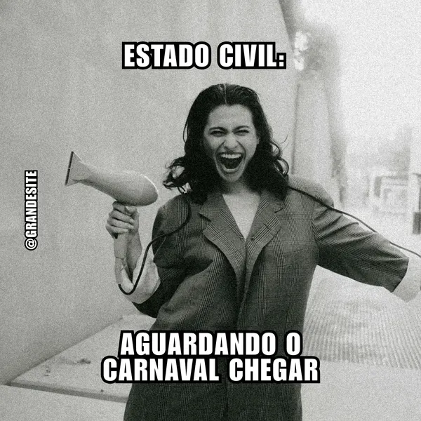 Meme em preto e branco de mulher rindo abertamente, segurando um secador de cabelo como microfone. Texto: 'ESTADO CIVIL: AGUARDANDO O CARNAVAL CHEGAR'. Transmite humor e antecipação para a folia, ideal para posts engajadores de Instagram e Facebook sobre o Carnaval.