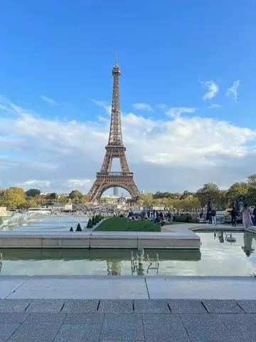 Torre Eiffel em Paris com Fonte e Céu Azul — Foto da Torre Eiffel em Paris, França, com uma fonte e céu azul com nuvens. Ideal para turismo e viagens.